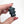 Hand holding a small black robot figurine against a white background
