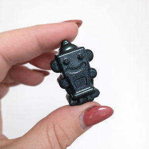Hand holding a small black robot figurine against a white background