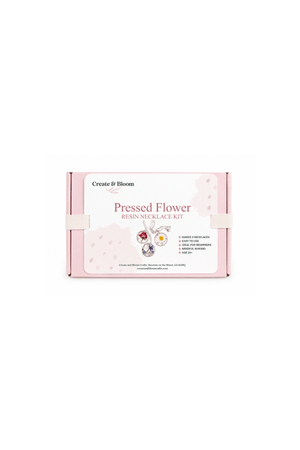 A pink and white product box for the 'Create & Bloom Pressed Flower Resin Necklace Kit' on a solid white background.